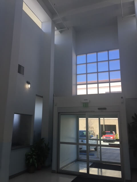 Bright entry lobby of the Desert Cities Kidney Dialysis Center with tall skylit walls and large glass doors providing natural daylight.