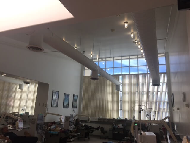 Dialysis treatment room featuring high ceilings, clerestory glazing, and exposed mechanical ducts designed to enhance airflow and natural light.