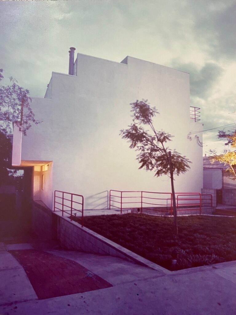 Exterior view of the Pier Street Condos in Santa Monica, featuring a stepped modern façade, minimal openings, and warm interior light glowing at dusk.