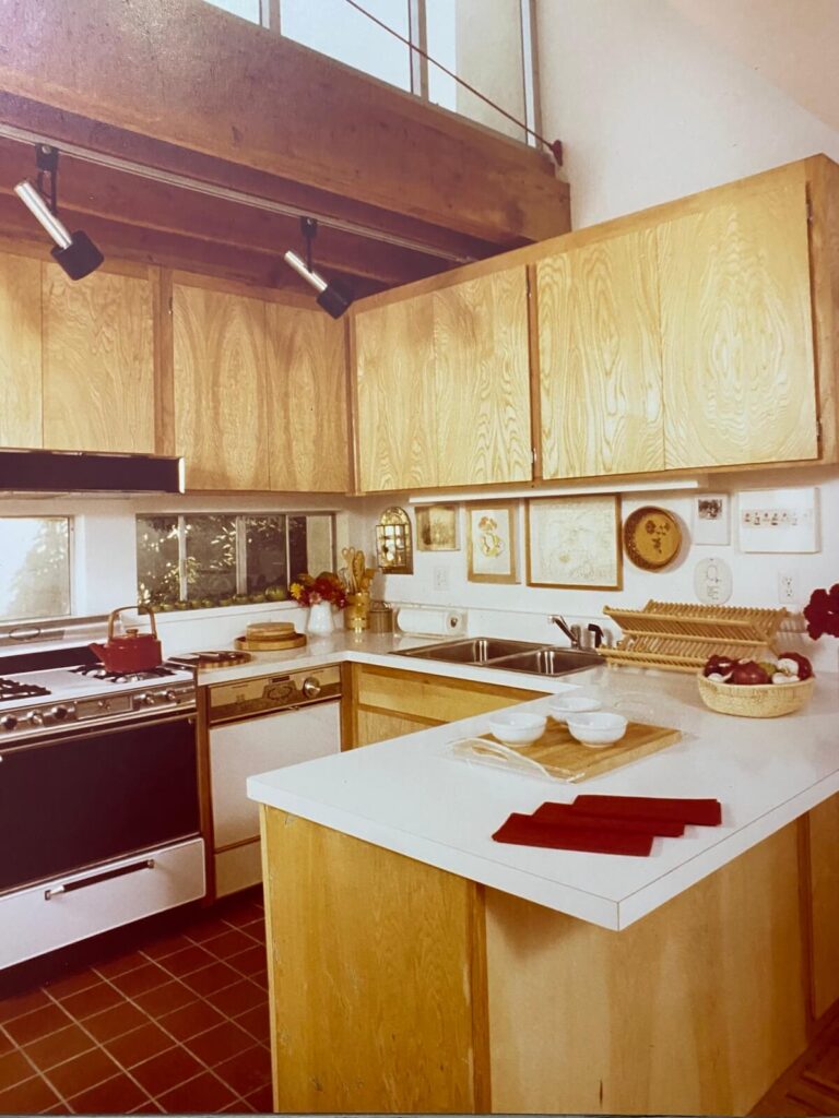 Kitchen interior at the Pier Street Condos in Santa Monica with natural wood cabinetry, white countertops, and an open loft overlooking the space.