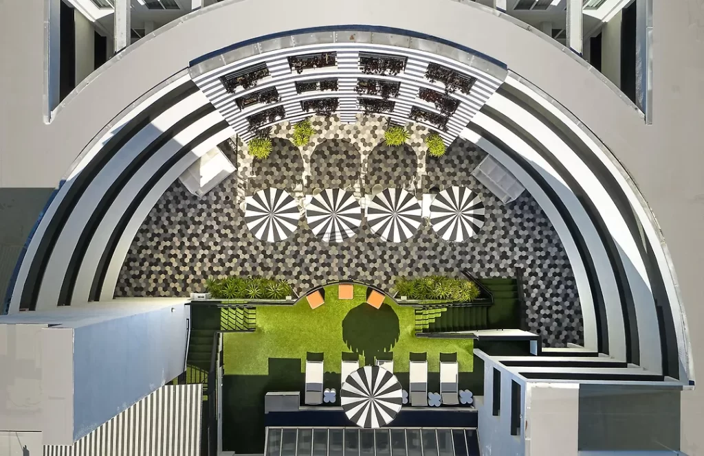 Aerial view of The Carlyle Inn courtyard in West Los Angeles showing geometric paving, umbrellas, and landscaped terraces.