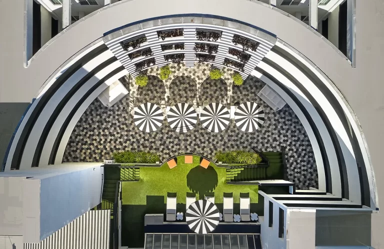 Aerial view of The Carlyle Inn courtyard in West Los Angeles showing geometric paving, umbrellas, and landscaped terraces.