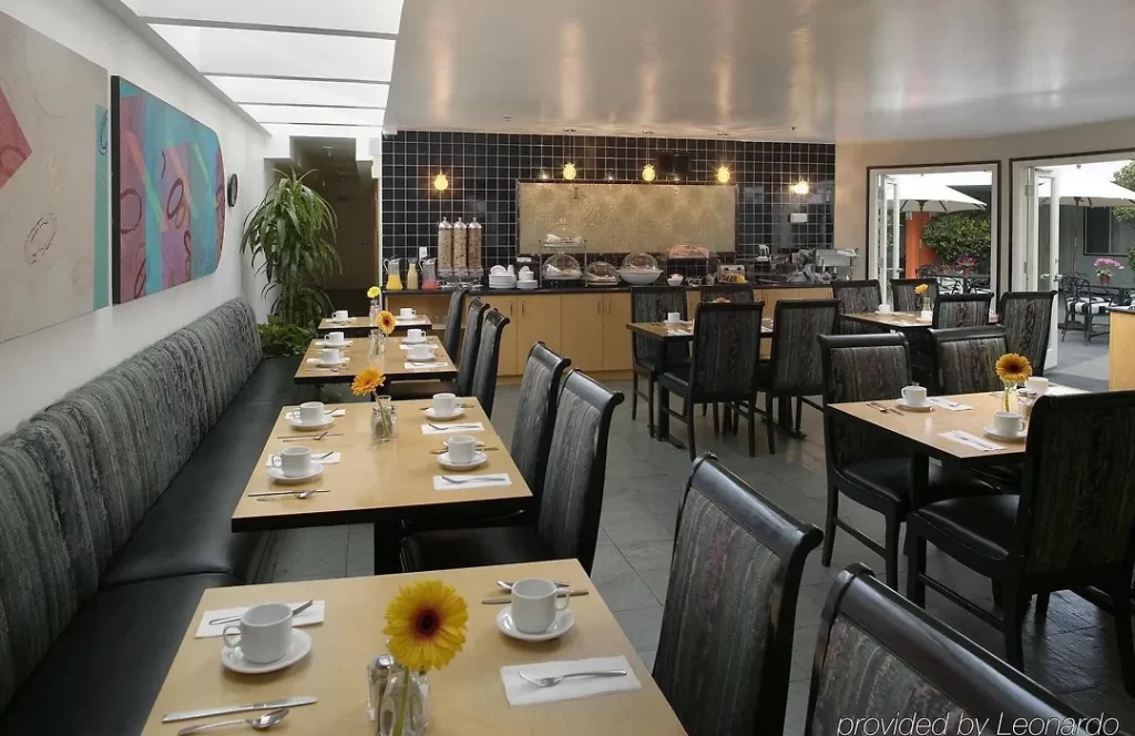 Interior dining space at The Carlyle Inn in West Los Angeles with communal tables, natural light, and buffet area.