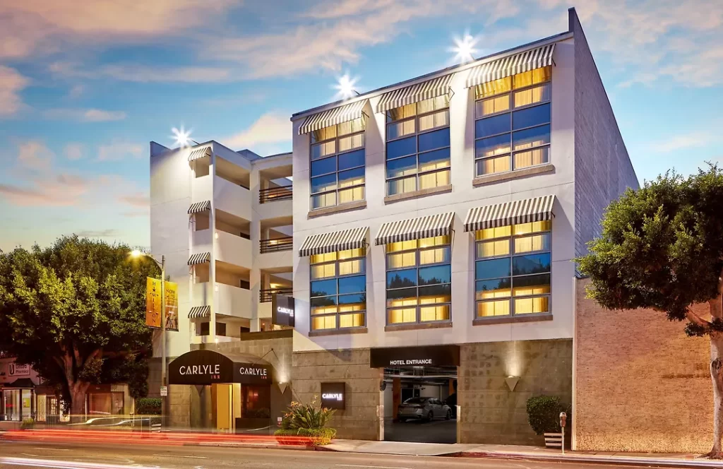 Street-level exterior of The Carlyle Inn in West Los Angeles illuminated at dusk with modern facade and hotel entrance.